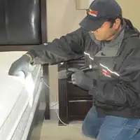 Bed bug inspection technician checking a mattress and bed frame for signs of infestation in Phoenix, AZ