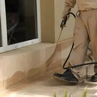 General pest control technician spraying exterior perimeter around a home in Phoenix, AZ