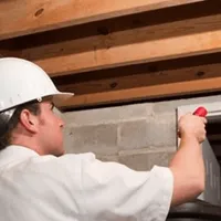 Termite inspection technician checking a basement wall and framing for termite activity in Phoenix, AZ
