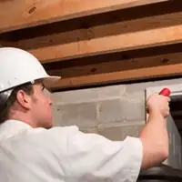 Termite inspection technician checking a basement wall and framing for termite activity in Phoenix, AZ